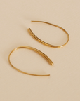 Gold hoop earrings on a beige background
