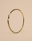 Gold hoop bracelet on a beige background