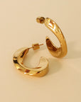 Gold hoop earrings on a beige background