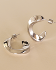 Silver hoop earrings on a beige background