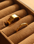Two rings sitting in a brown jewellery box