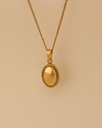 Gold necklace with an oval pendant on a beige background