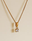 Gold necklace with a diamond pendant on a beige background