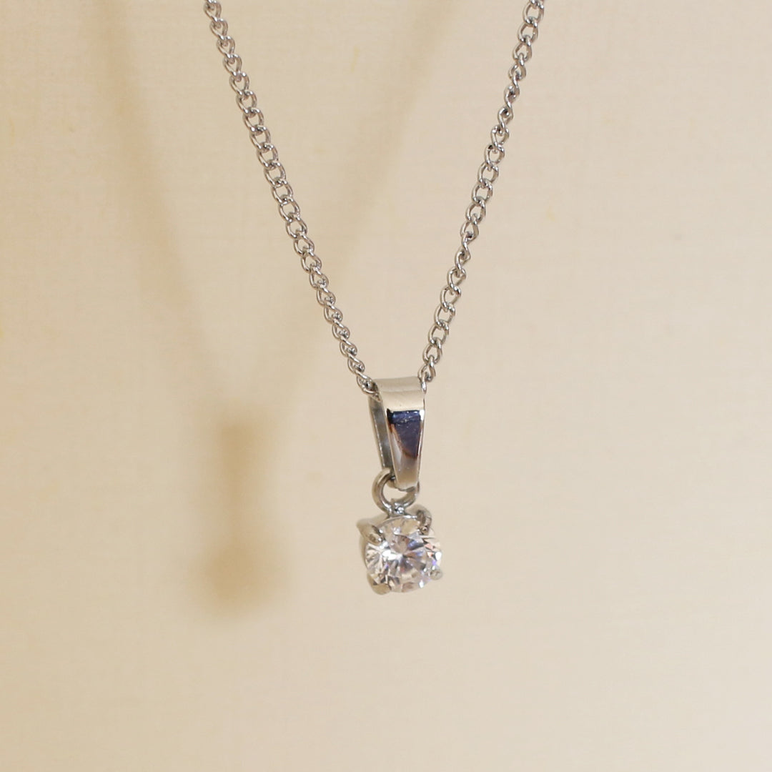 Silver necklace with a diamond pendant on a beige background