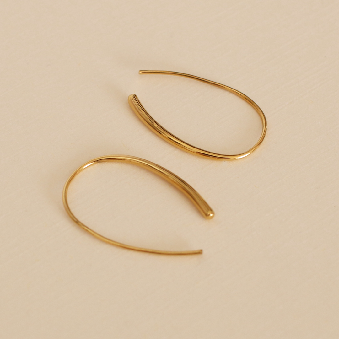 Gold hoop earrings on a beige background