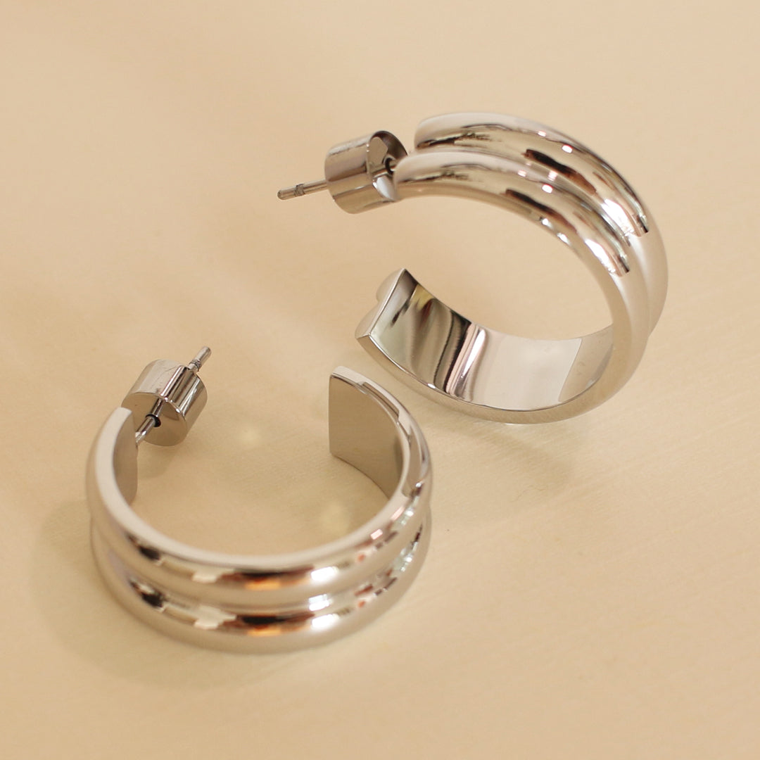 Pair of silver hoop earrings on a beige background