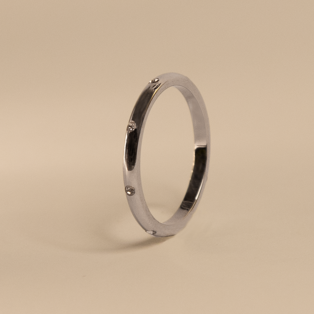 Silver ring with small diamonds on a beige background