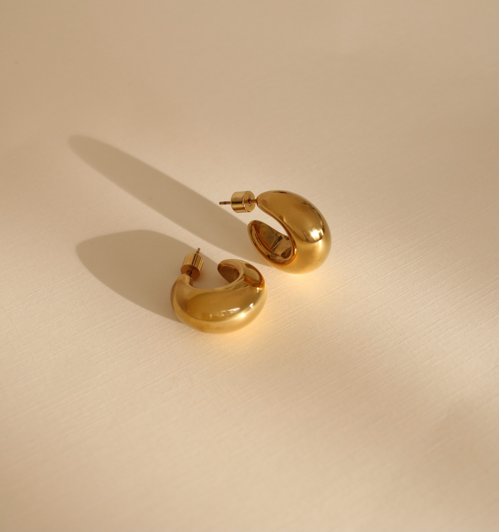 Pair of gold hoop earrings on a beige background