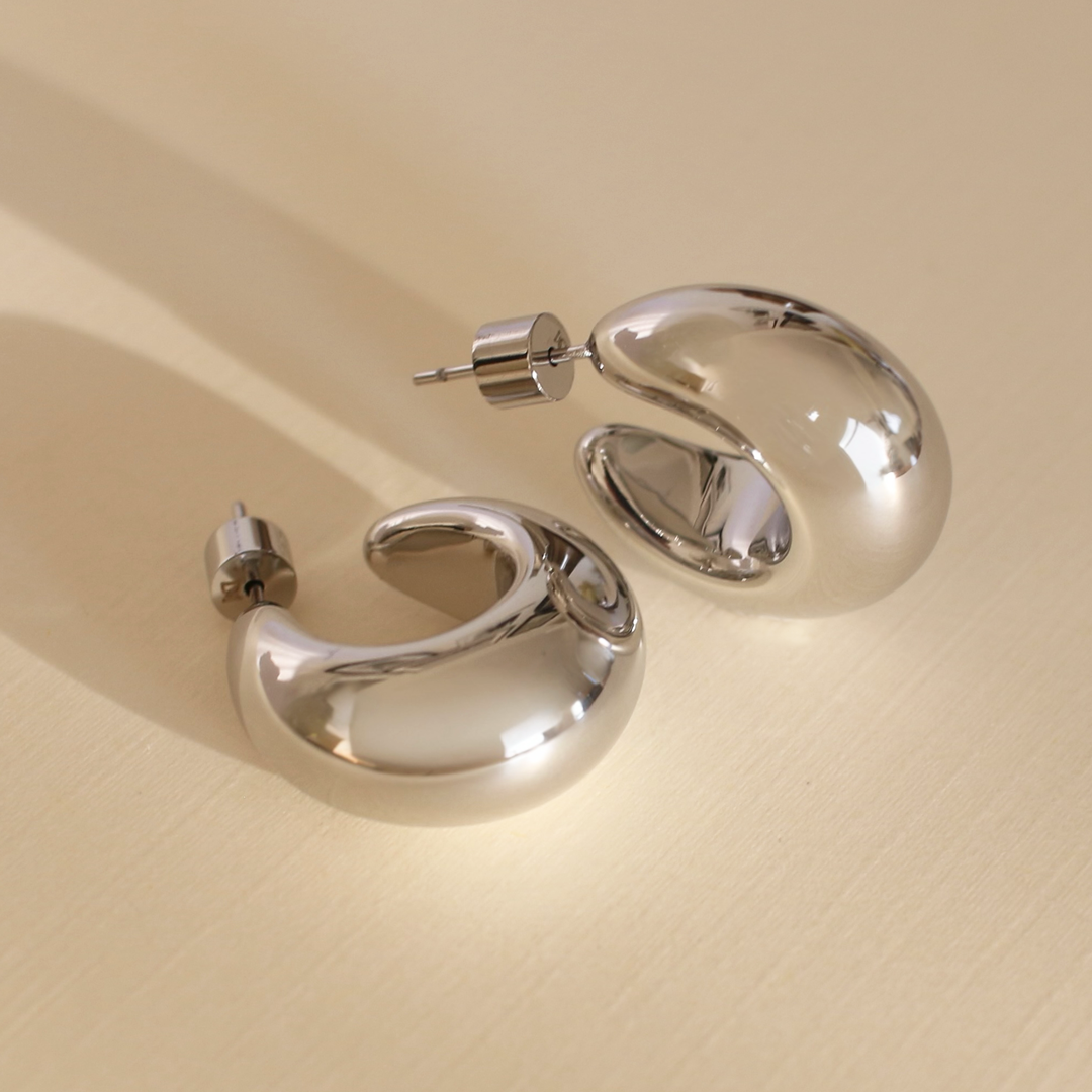 Pair of silver hoop earrings on a beige background