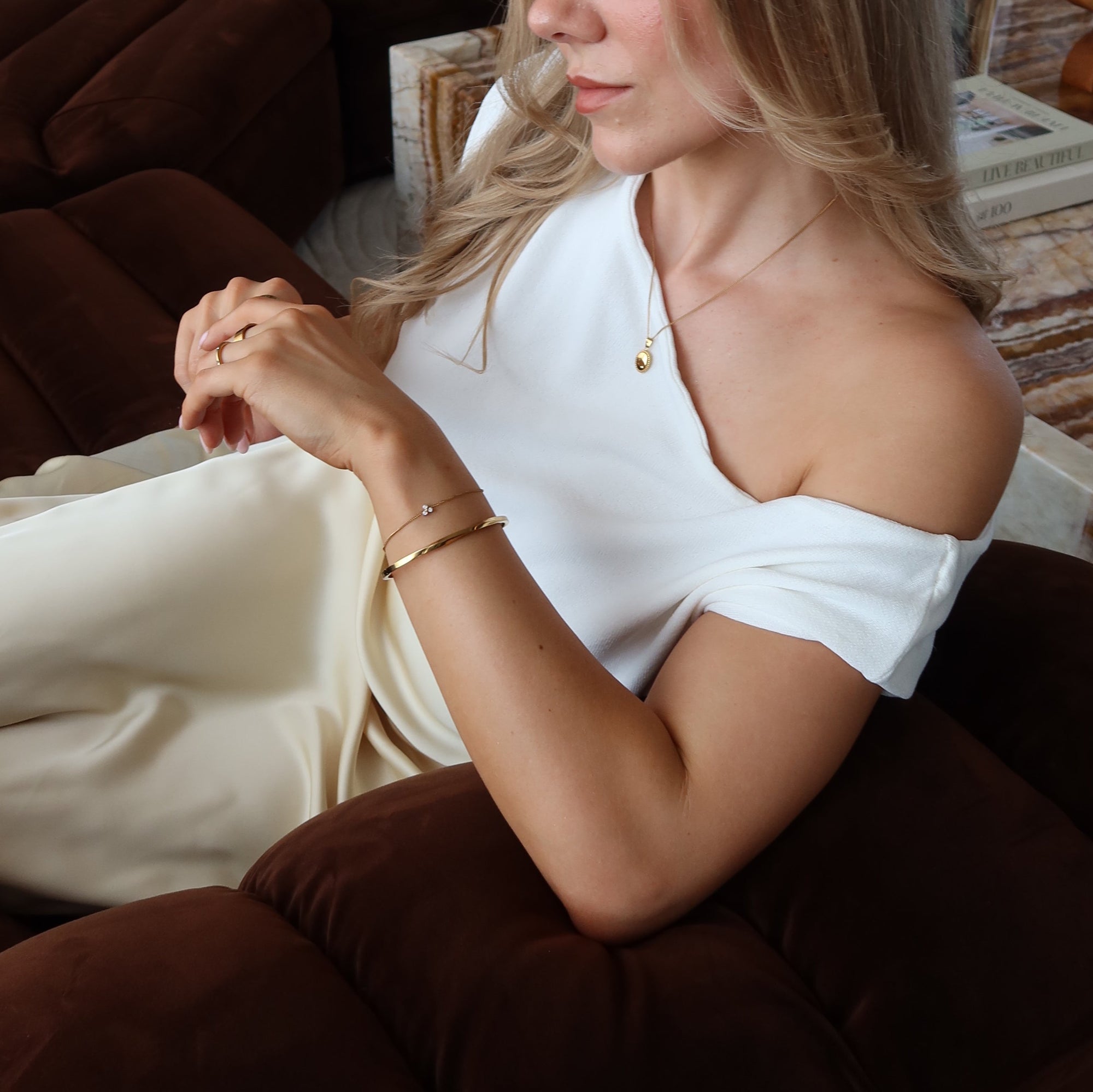 Woman in a white dress sitting on a brown couch with a blurred background