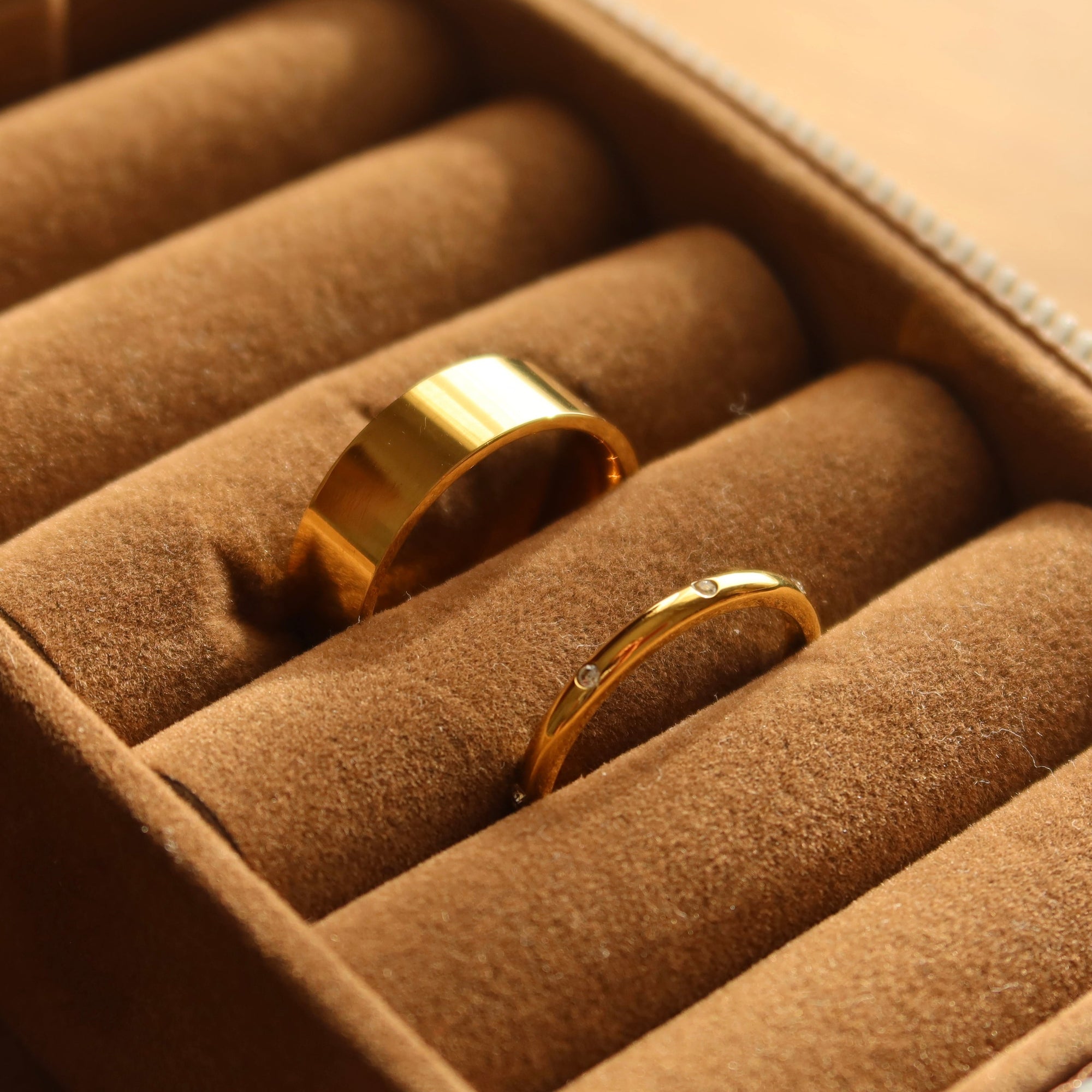 Two rings sitting in a brown jewellery box