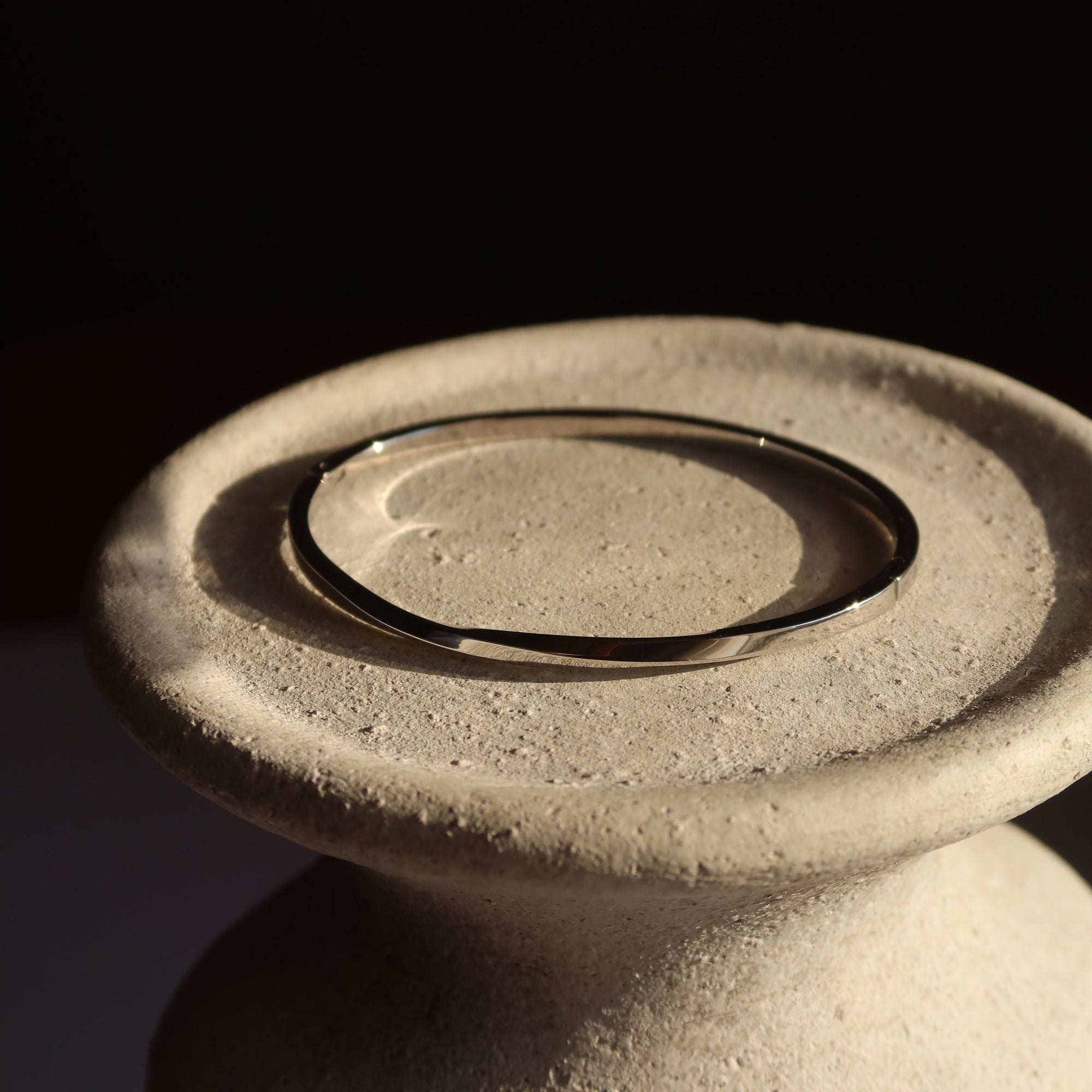 Close-up of a silver bracelet on a textured ceramic background