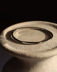Close-up of a silver bracelet on a textured ceramic background