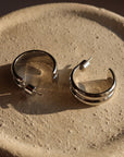 Pair of silver hoop earrings on a textured beige surface