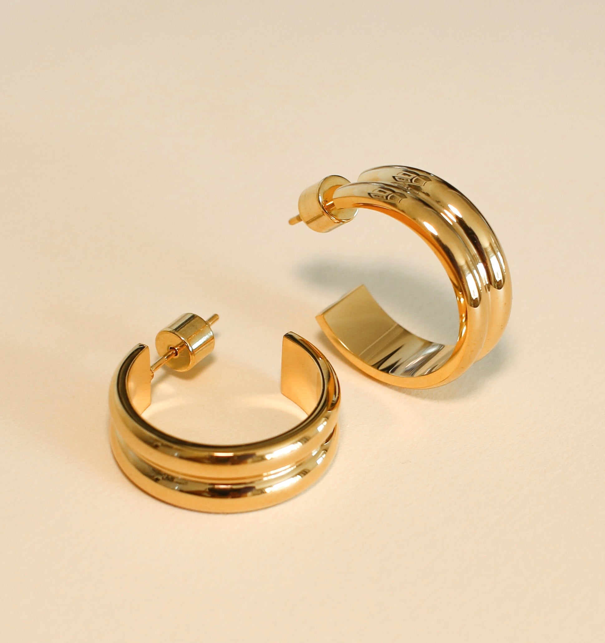 Gold hoop earrings on a beige background
