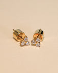 Gold earrings with small diamonds on a beige background